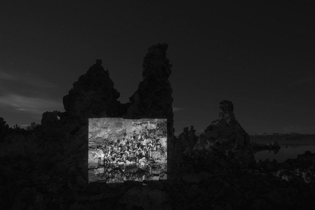 莫诺湖夜间岩层的黑白照片. 人们聚集在一起参加补水仪式的照片投射在岩层上.